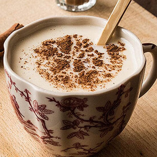 Çiçekli bir fincan içinde lezzetli görüntüsüyle iştah kabartan salep içeceği ve aroma katmak için içine eklenmiş iki parça rulo tarçın