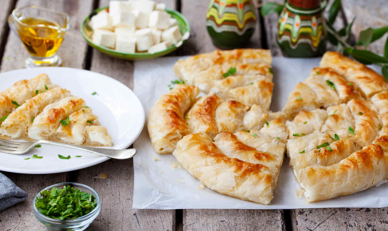 peynirli börek tarifleri arasında misafirlerinizi memnun edecek dilimlenmiş börek, çay ve peynirin olduğu bir masa