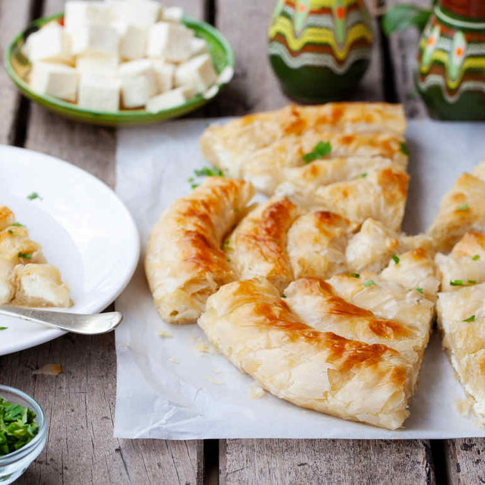 peynirli börek tarifleri arasında misafirlerinizi memnun edecek dilimlenmiş börek, çay ve peynirin olduğu bir masa