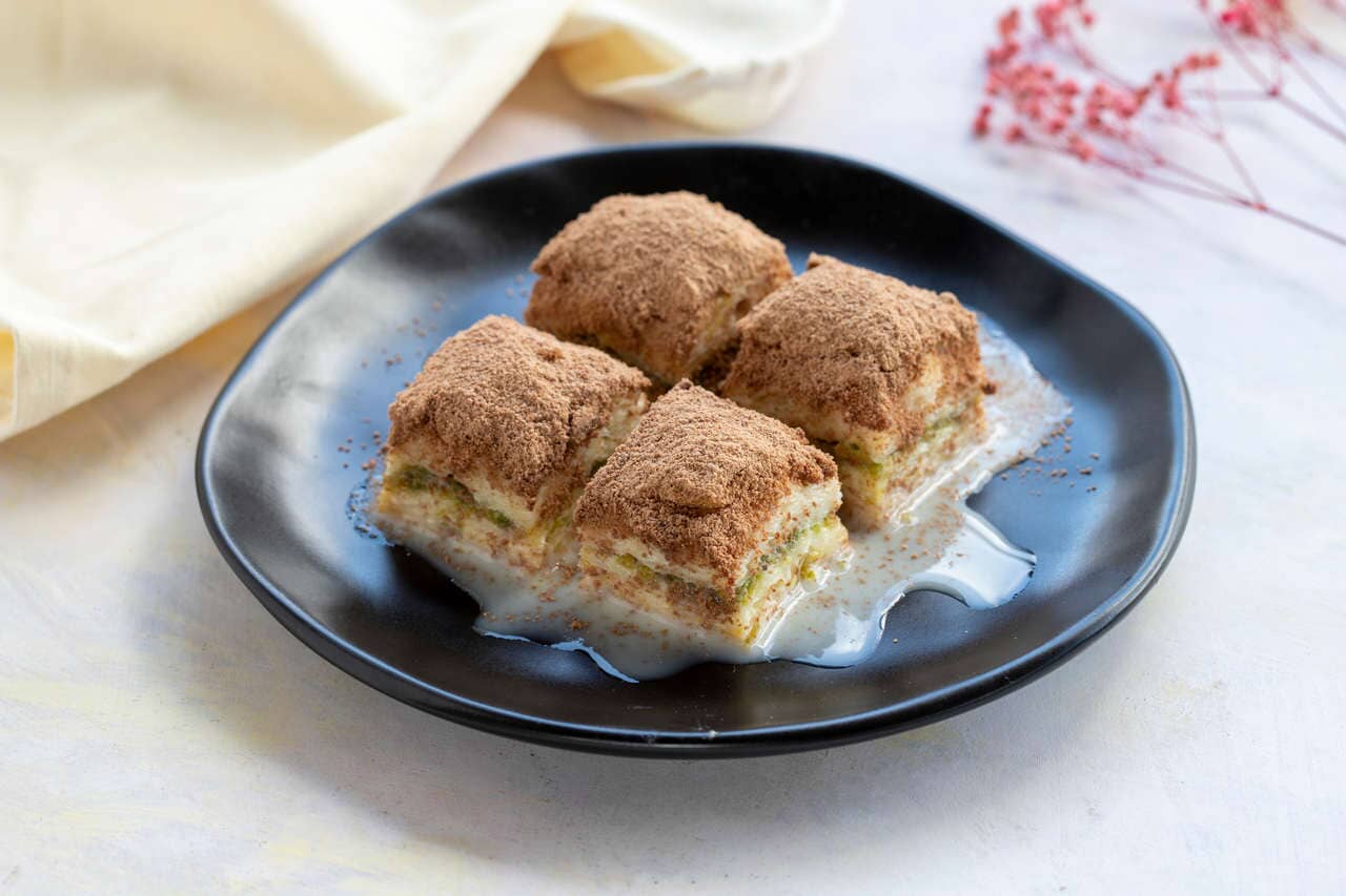 masanın üzerinde duran bir porsiyon soğuk baklava
