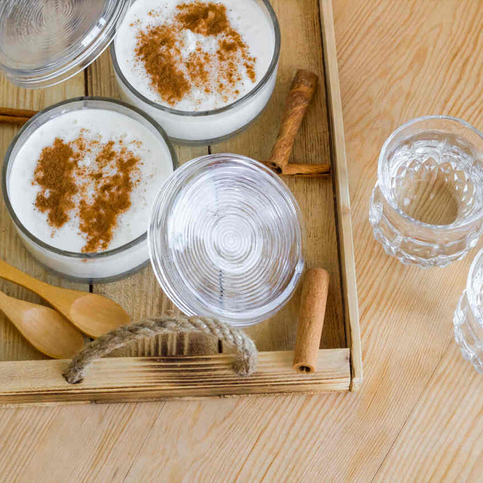 yanında iki su bardağı olan tarçınlı sütlaç kaseleri